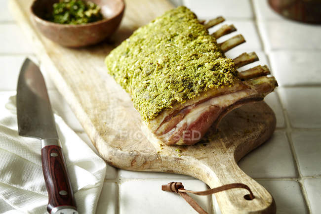 Rack d'agneau avec croûte d'herbes sur planche à découper — Photo de stock