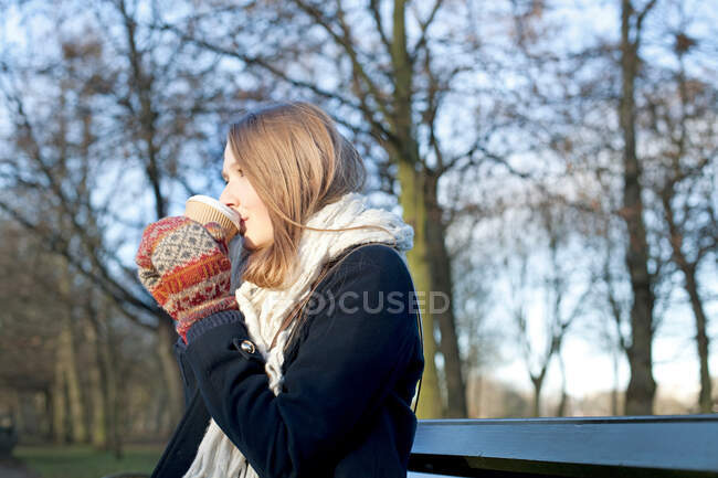 Mulher tomando café no banco do parque — Fotografia de Stock