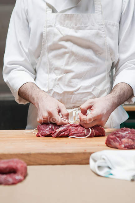 Butcher tying beef tenderloin with string — Stock Photo