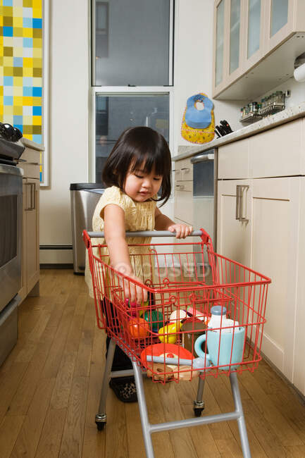 A girl pushing a toy trolley — Stock Photo