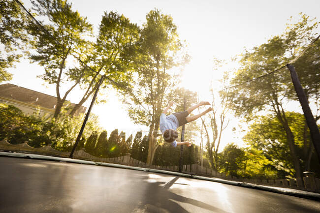 Menino fazendo salto mortal em trampolim grande, visão de baixo ângulo — Fotografia de Stock