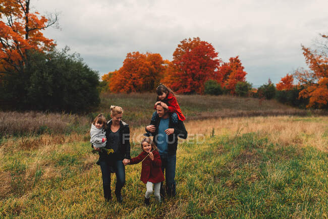 Середня доросла сім'я з трьома доньками, які гуляють разом у сільській місцевості — стокове фото