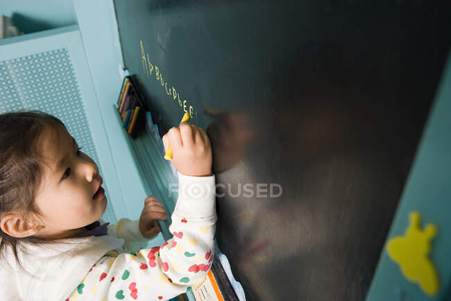 Girl writing on a blackboard — Stock Photo