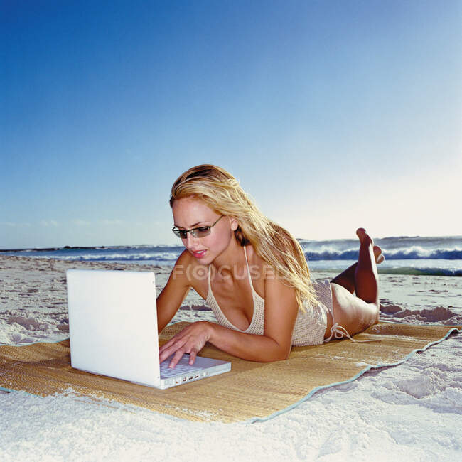 Femme avec ordinateur portable sur la plage — Photo de stock
