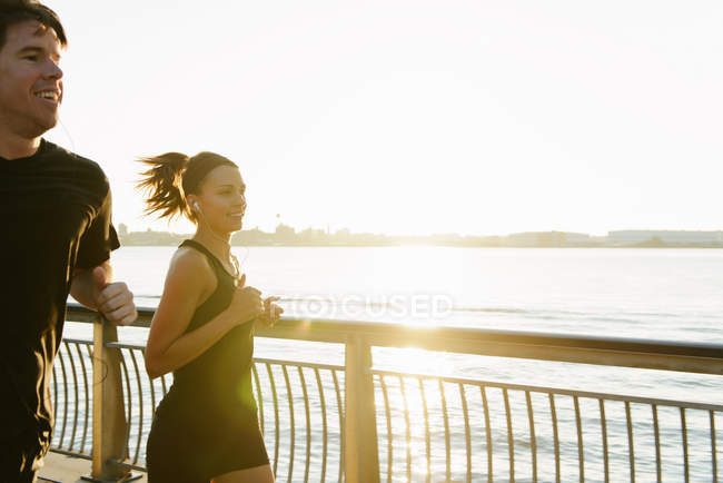 Jogging couple running along riverside early morning — Stock Photo