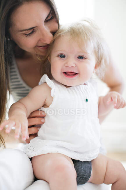 Bébé fille assis sur les genoux de la mère — Photo de stock