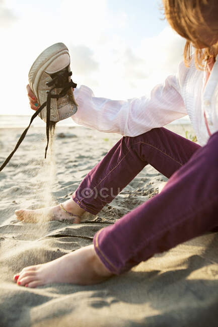 Mädchen leert Schuh am Strand — Stockfoto