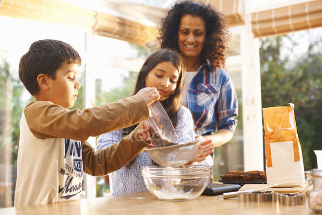 Mother and children baking in kitchen at home — Stock Photo