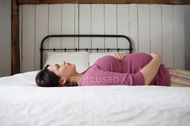 Беременная женщина лежит на кровати — стоковое фото