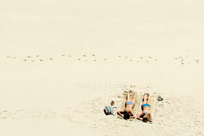 Две девушки загорают на песчаном пляже — стоковое фото