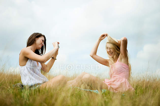 Молодая женщина фотографирует друга, позирующего с зонтиком — стоковое фото