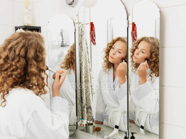 Mujer joven aplicando maquillaje en el espejo - foto de stock