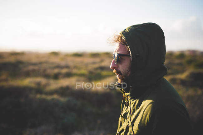 Portrait d'un homme adulte moyen portant une cagoule en anorak sur le terrain — Photo de stock