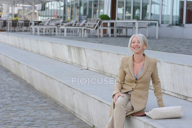 Senior woman sitting on steps in city — Stock Photo