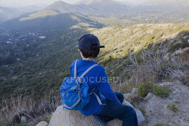 Boy sitting on boulder looking out over Andes, Valparaiso, Chile — Stock Photo