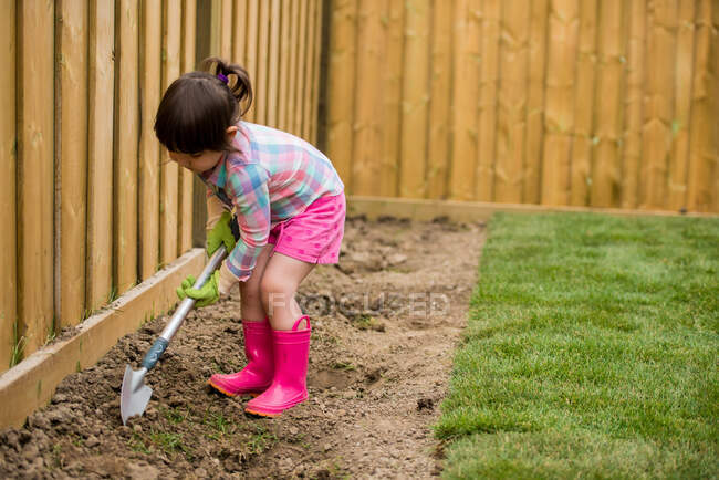 Chica joven cavando en el jardín - foto de stock