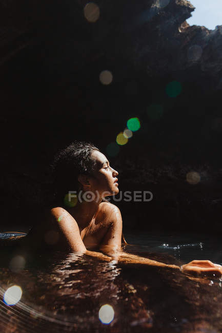 Mujer en la cueva llena de agua y mirando hacia otro lado, Oahu, Hawaii, EE.UU. - foto de stock