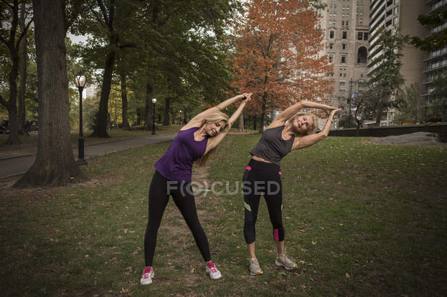 Due amiche mature che si allenano nel parco, piegandosi lateralmente — Foto stock