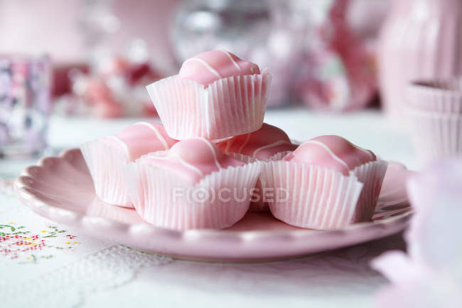 Primer plano de plato con caramelos envueltos en rosa - foto de stock