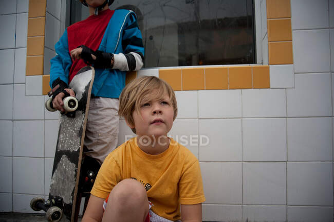 Niños con monopatín sentado al aire libre - foto de stock