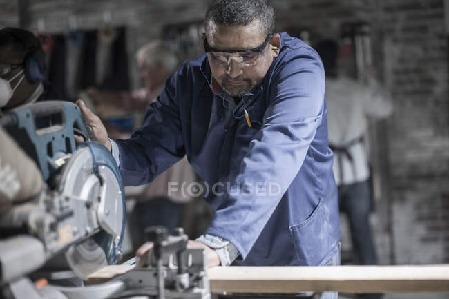 Cape Town, South Africa, machinist sawing off wood using machine in workshop — Stock Photo