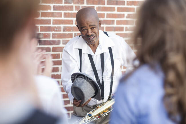 Кейптаун, Южная Африка, человек с саксофоном благодарит гостя — стоковое фото