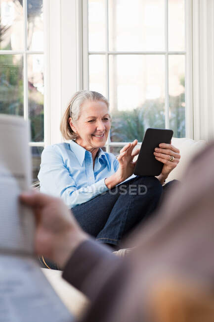 Mujer mayor usando libro electrónico - foto de stock