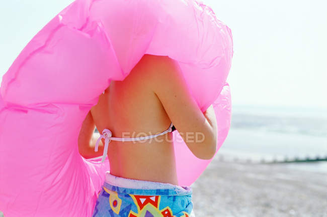 Rear view of girl on beach with inflatable lifebelt — Stock Photo