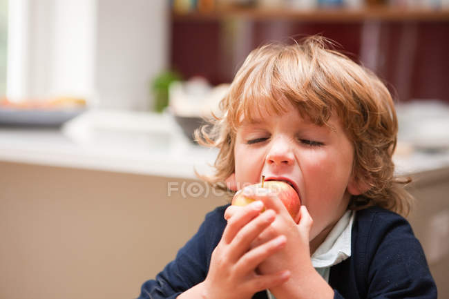 Jovem menino comendo uma maçã — Fotografia de Stock