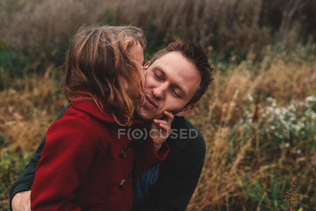 Дівчина цілує батька на щоці в полі — стокове фото
