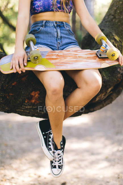 Девочка держит пенниборд на коленях — стоковое фото