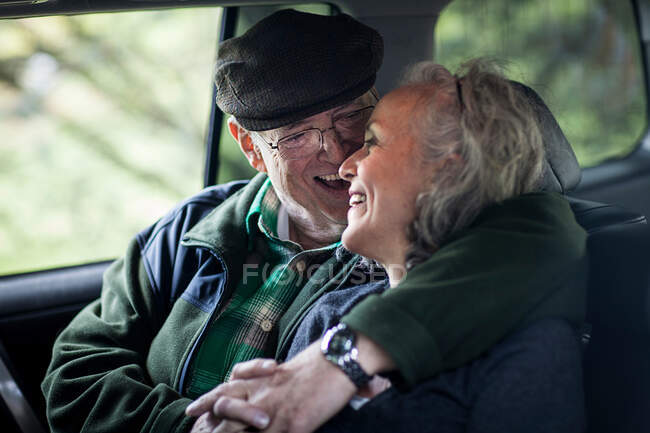 Casal sênior abraçando na parte de trás do carro — Fotografia de Stock
