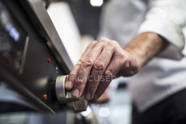 Chef turning on oven, close-up — Stock Photo