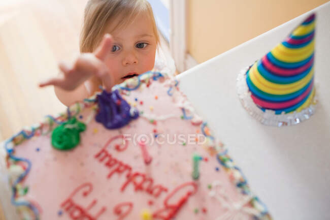 Chica tocando pastel de cumpleaños - foto de stock