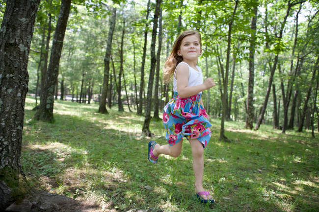 Kleines glückliches Mädchen läuft im Wald — Stockfoto