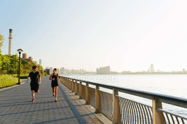 Jogging couple running along riverside — Stock Photo