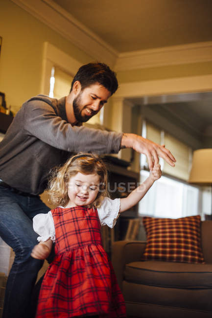 Menina dançando com o pai na sala de estar — Fotografia de Stock