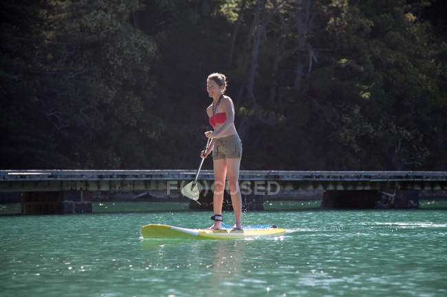 Femme adulte moyenne debout paddleboard en mer — Photo de stock
