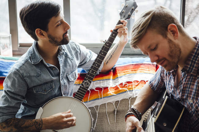 Male couple at home, play guitar and banjo — Stock Photo