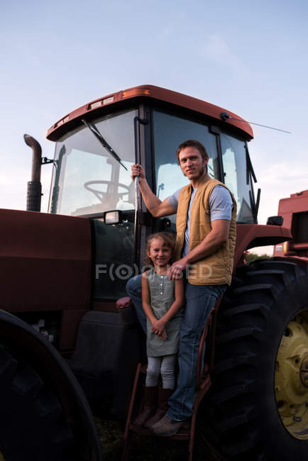 Портрет отца и дочери возле трактора — стоковое фото