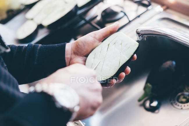 Homem fazendo cortes em metades de beringela — Fotografia de Stock