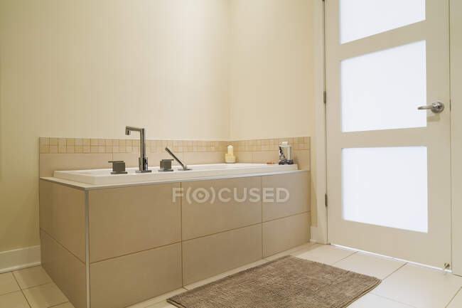 Впитывающая ванна заключена в керамическую плитку базы в ванной комнате отремонтированной квартиры на первом этаже в старом жилом коттедже стиле — стоковое фото