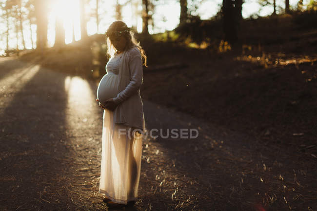 Mulher grávida em luz solar tocando estômago — Fotografia de Stock