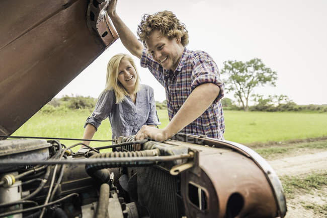 Young man and girlfriend checking jeep engine — Stock Photo