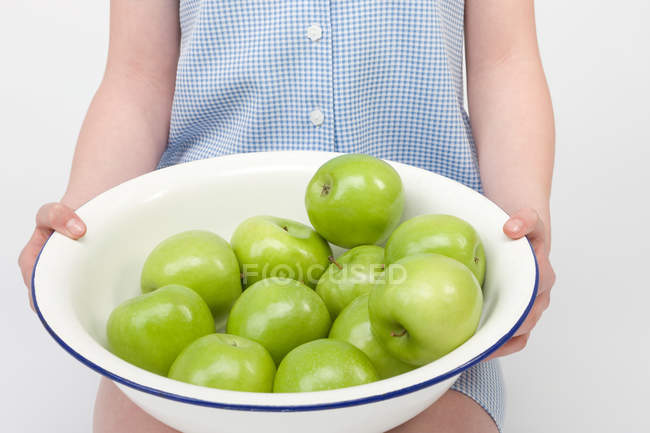 Kid holding bowl of ripe green apples — Stock Photo