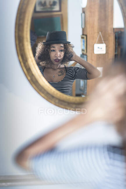 Cute young woman at home looking at herself in mirror — Stock Photo