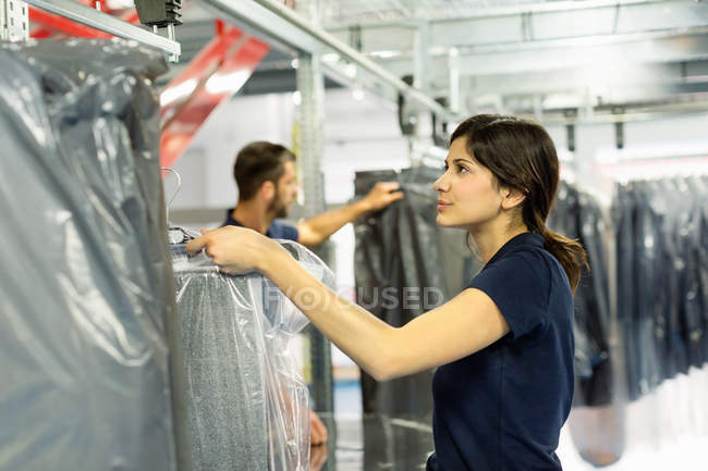 Trabajadores de almacén preparando pedidos de prendas de vestir en almacén de distribución - foto de stock