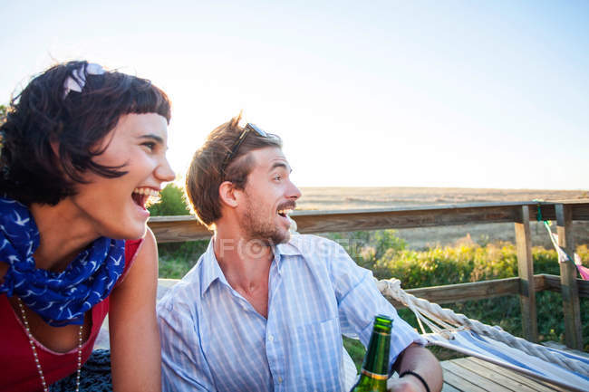 Giovane coppia seduta sul balcone soleggiato e sorridente — Foto stock