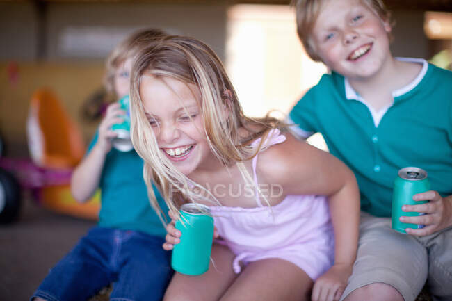 Children drinking soda in garage — Stock Photo