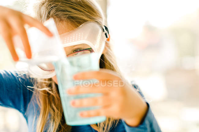 Mädchen macht naturwissenschaftliches Experiment, gießt Flüssigkeit — Stockfoto